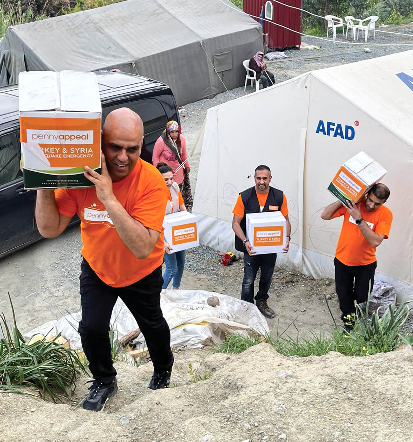 Penny Appeal volunteers carrying boxes of aid labeled 'Turkey & Syria Earthquake Emergency' as they deliver essential supplies to those in need following the disaster.